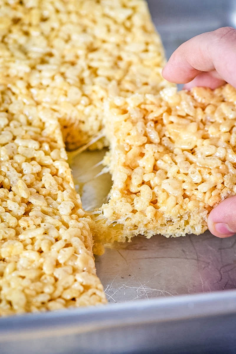 hand pulling gooey Rice Krispie treats out of pan