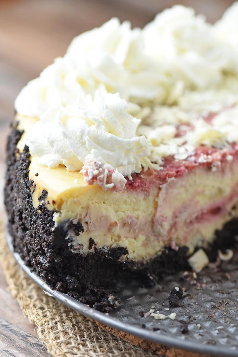 sliced white chocolate raspberry swirl cheesecake with chocolate cookie crust on springform pan bottom