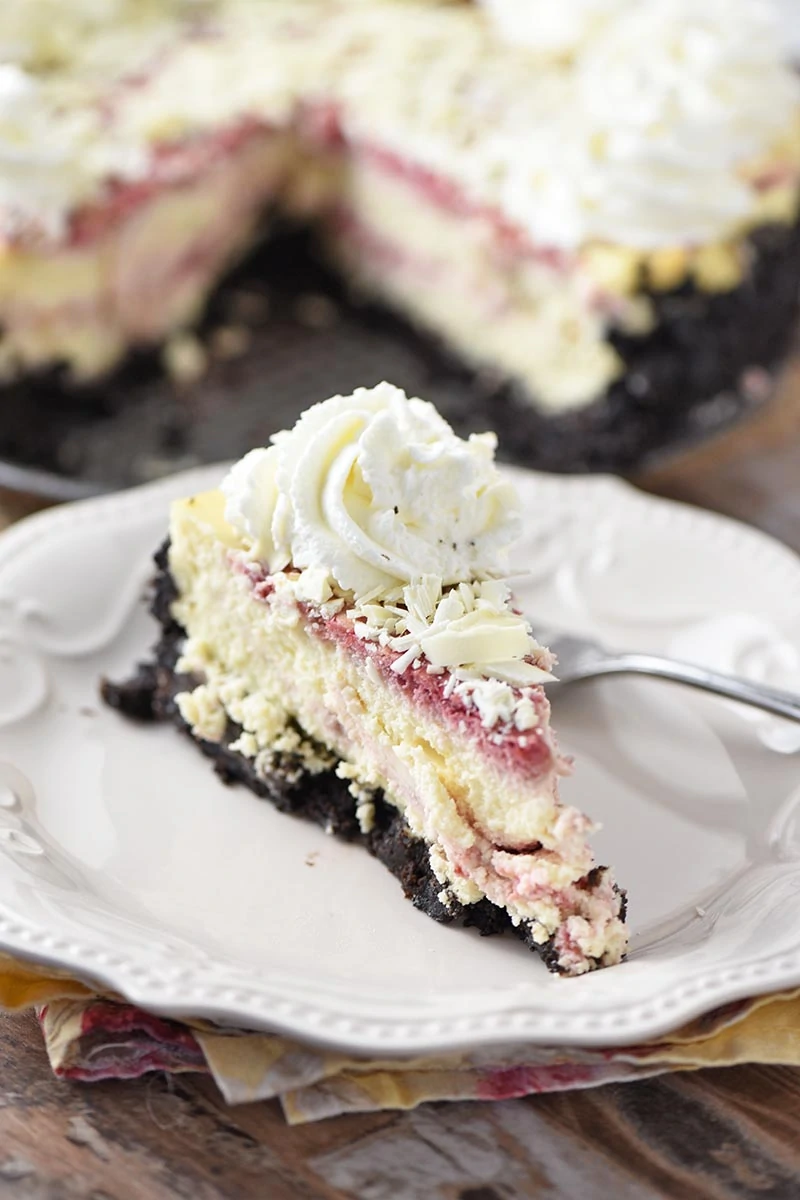 slice of white chocolate raspberry cheesecake on white plate with fork