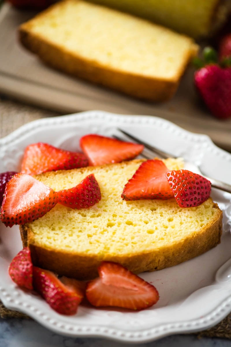 slice of pound cake with strawberries on white plate with fork