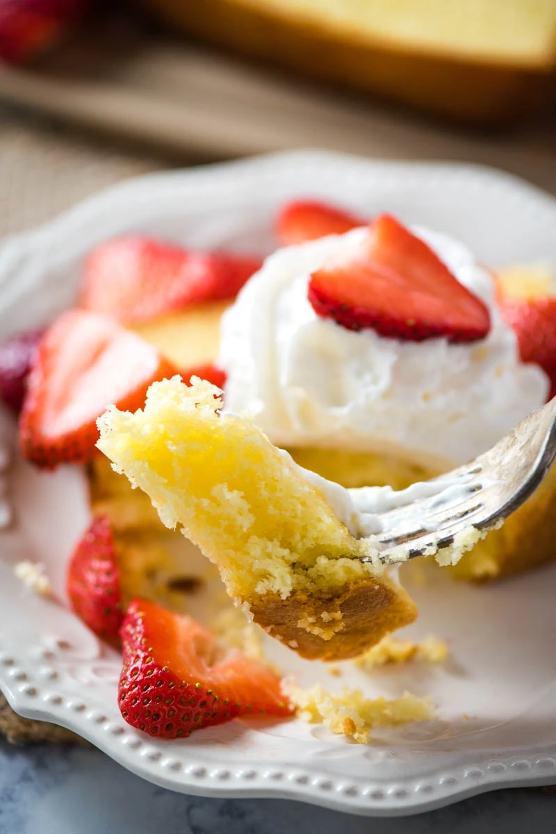 bite of freshly baked pound cake on fork with whipped cream