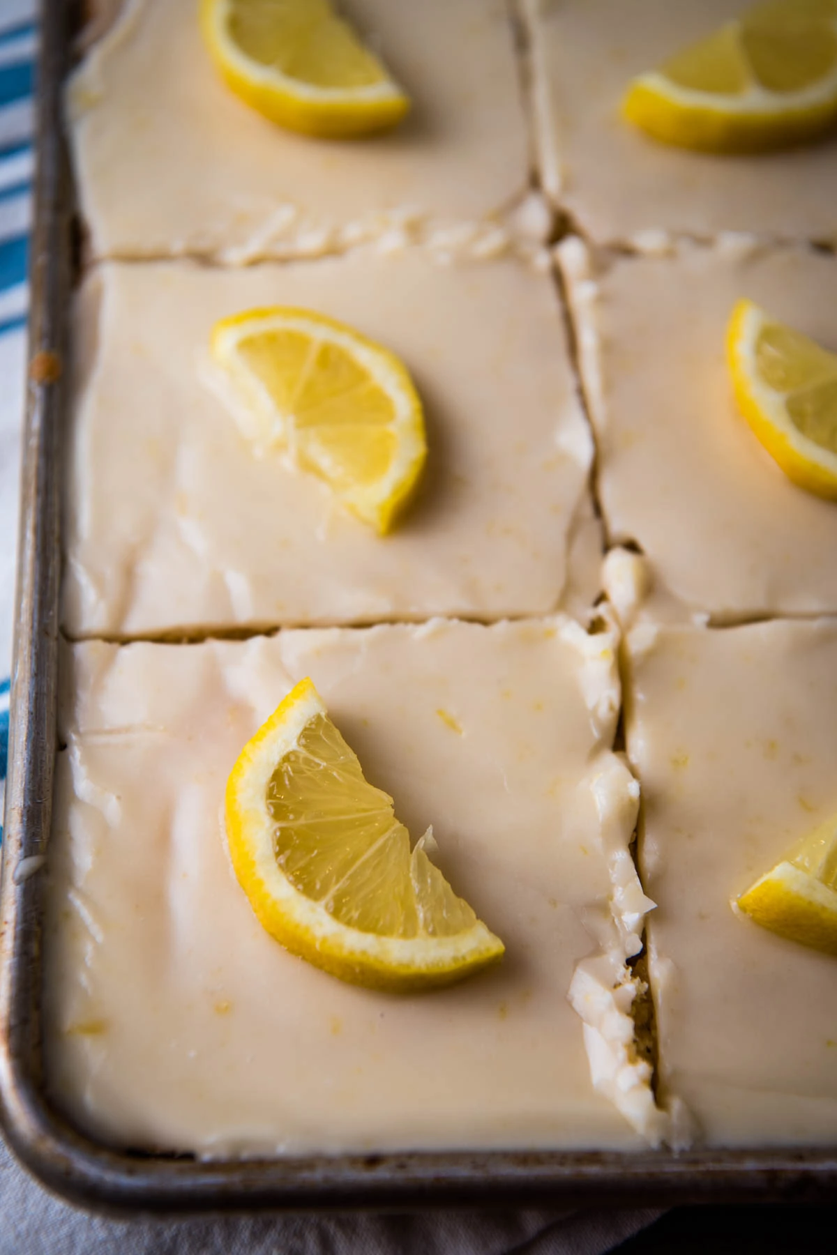 lemon Texas sheet cake topped with cooked lemon frosting and fresh lemon slices in a large sheet cake pan