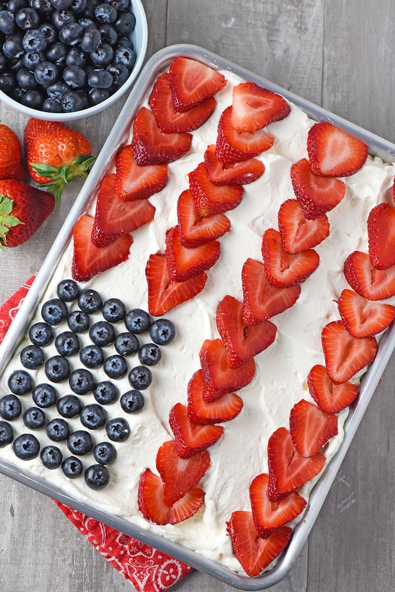 strawberry and blueberry American flag cake on wood countertop with berries