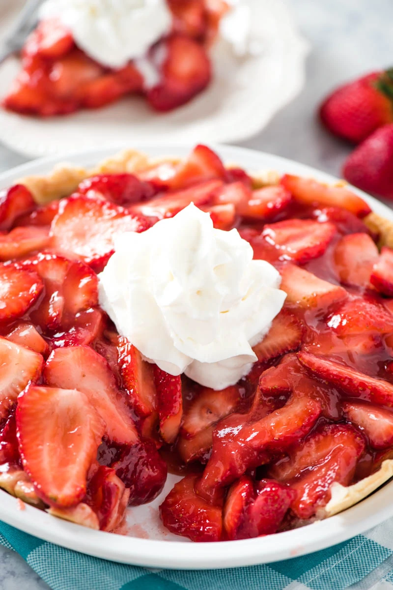 fresh strawberry pie recipe, made in white pie plate with big dollop of whipped cream