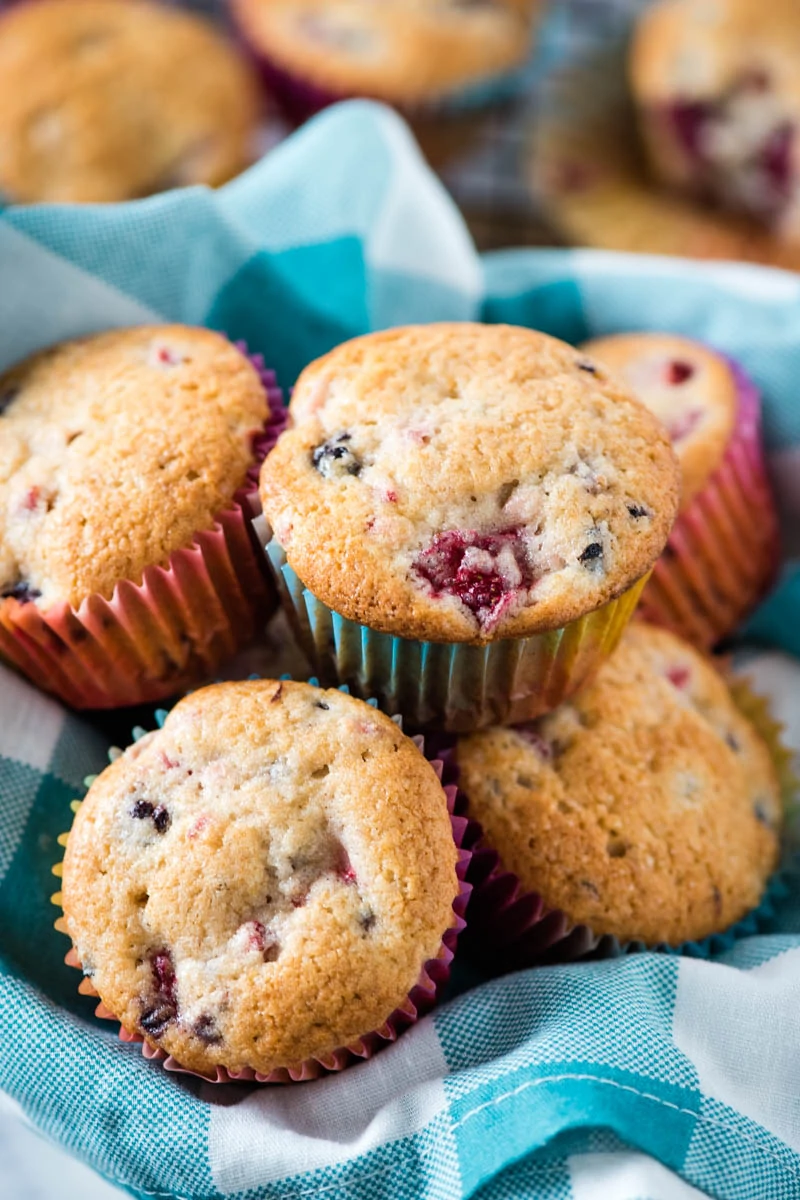 freshly baked blackberry and strawberry muffins in basket with teal gingham napkin