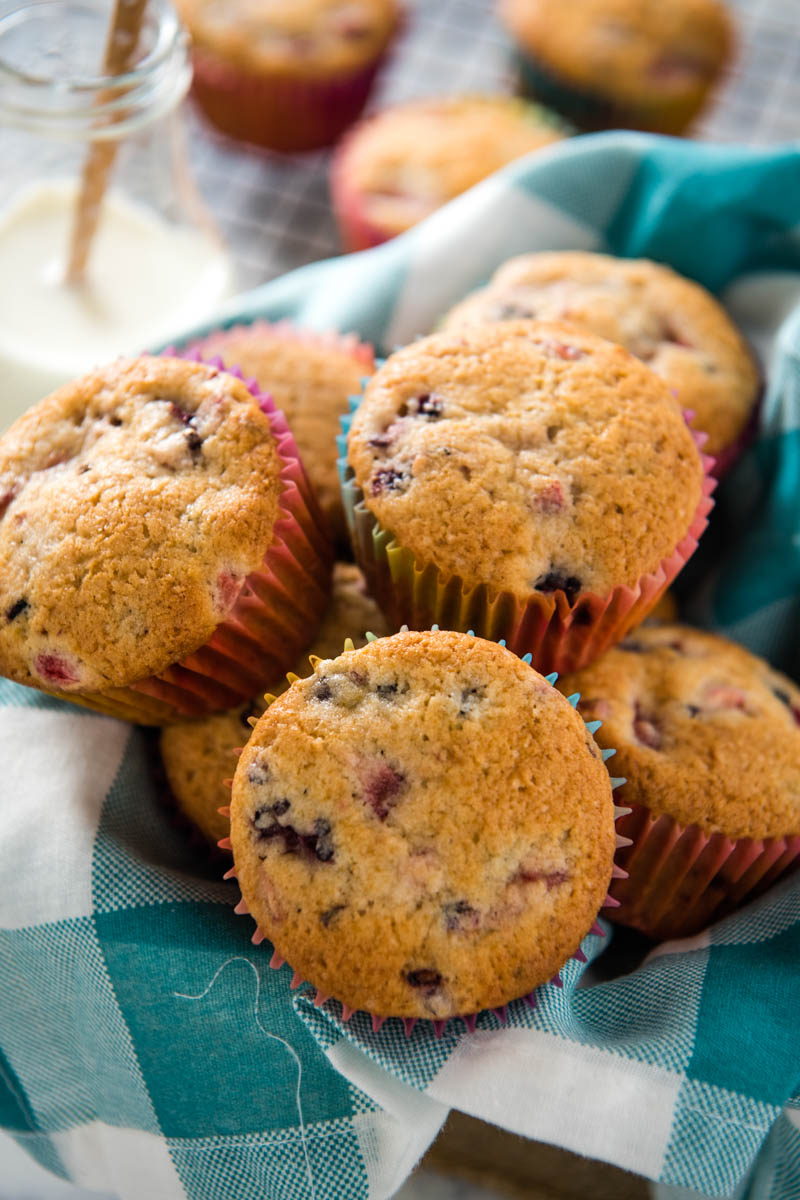 berry muffins in gingham lined basket with jar of milk