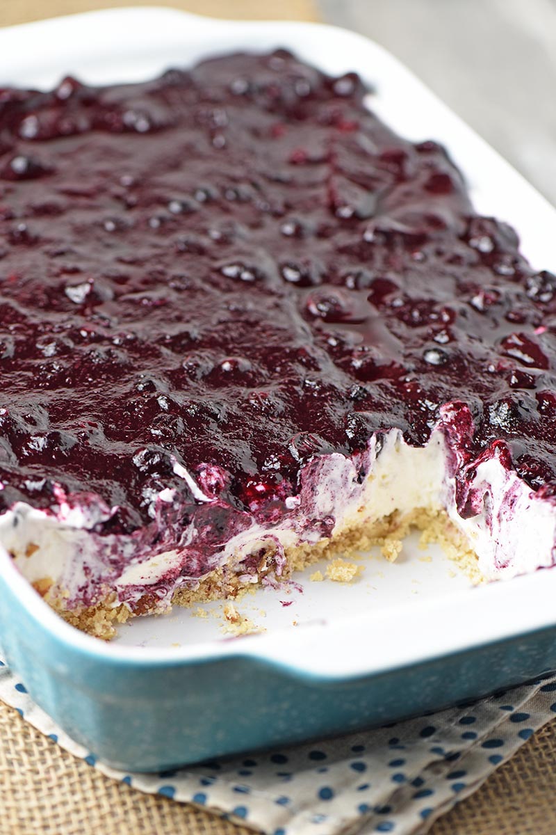 sliced blueberry dessert with no bake cream cheese filling in blue baking dish