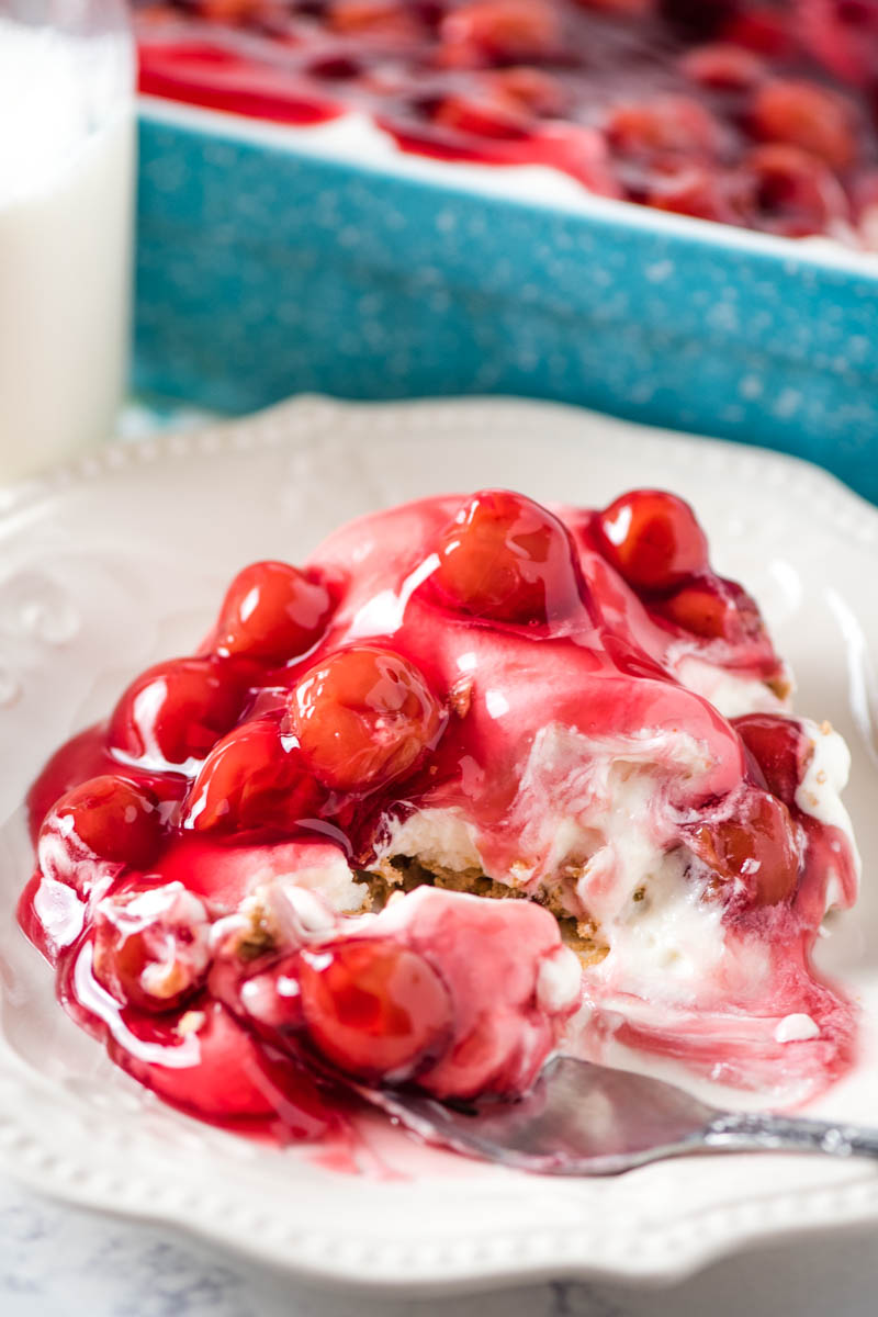 serving of no bake cherry dessert on white plate with fork