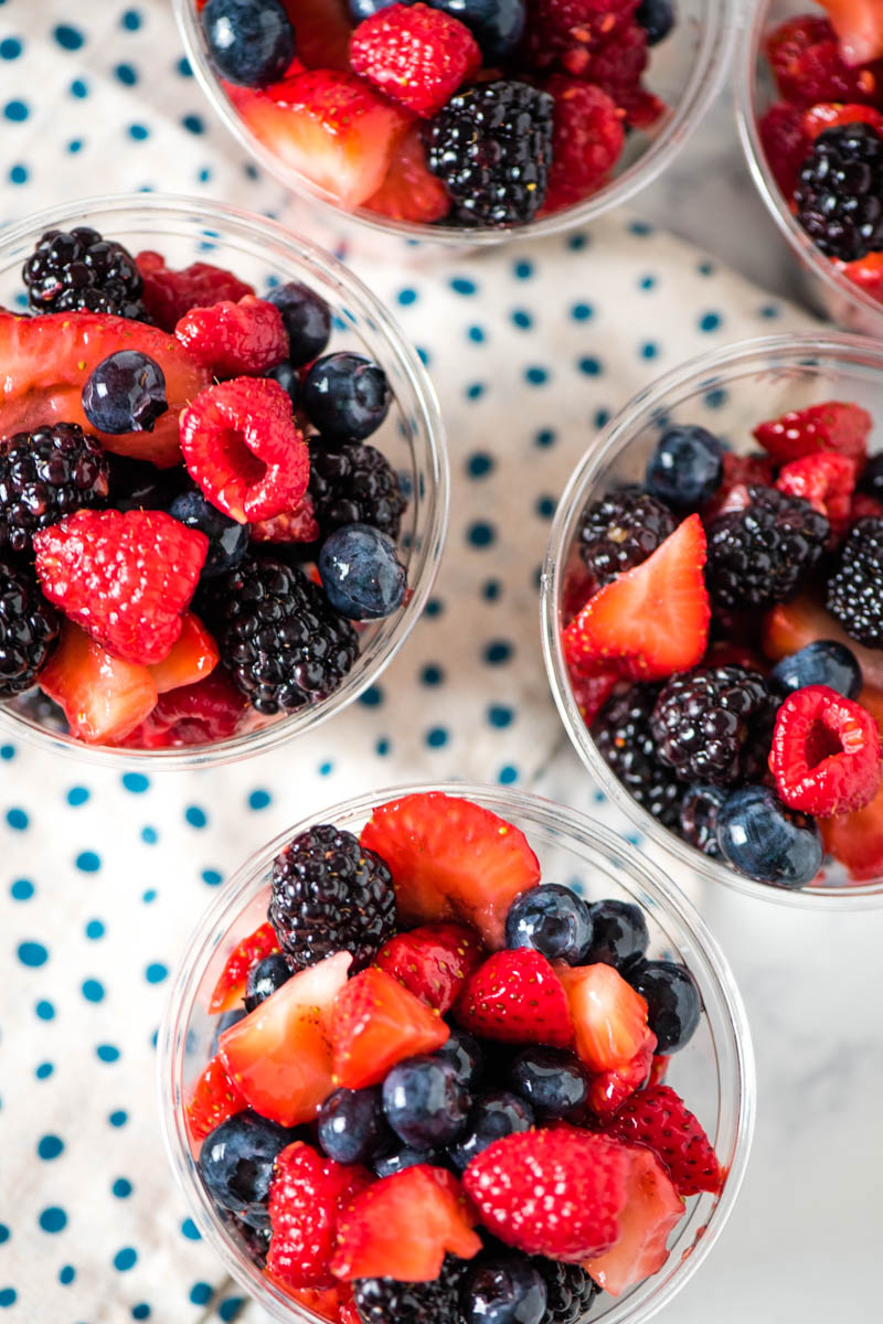 homemade fruit cups made with mixed berries and plastic cups on polka dot napkin