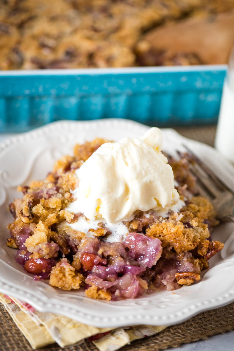 cherry dump cake with scoop of vanilla ice cream on white plate with fork