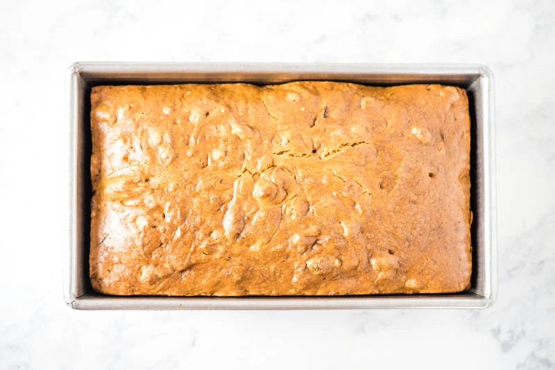 baked zucchini bread in metal loaf pan on white marble countertop