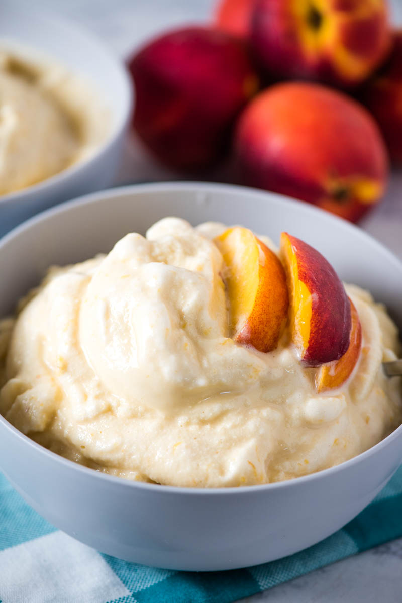 old-fashioned peach ice cream in white bowl with fresh peach slices