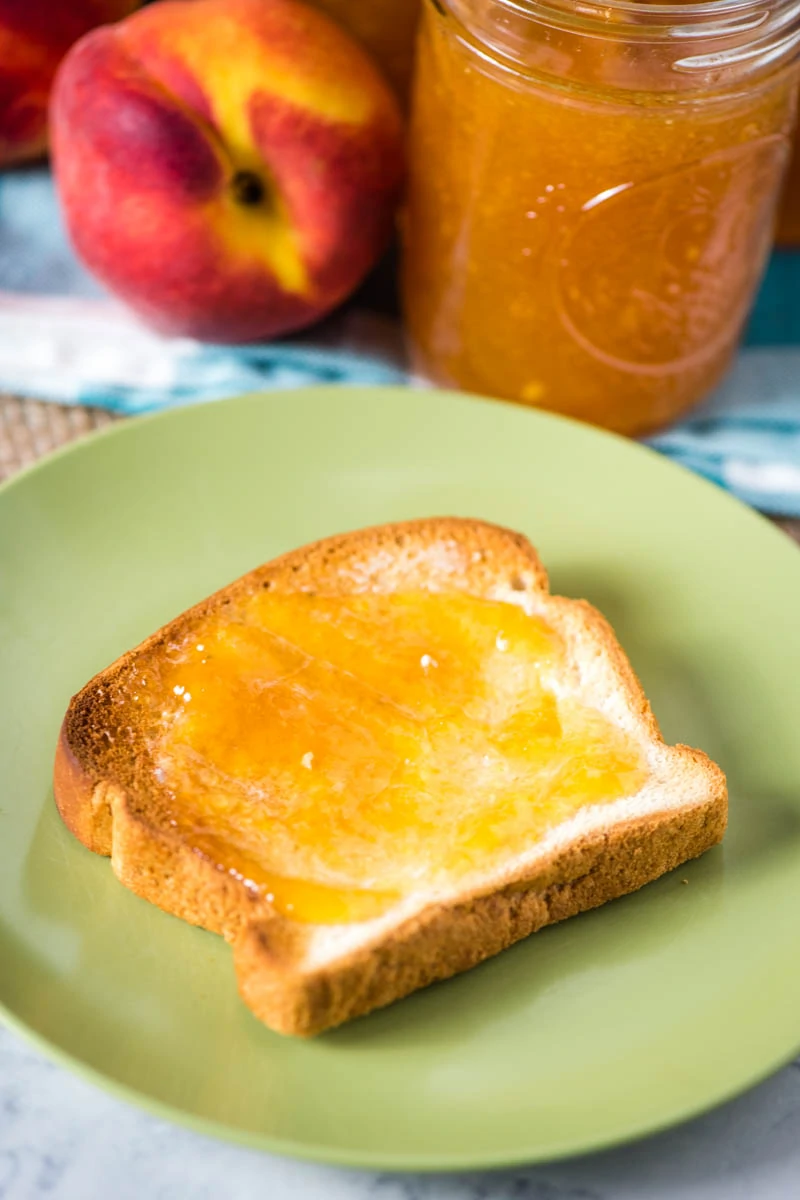 peach freezer jam spread on toast on green plate