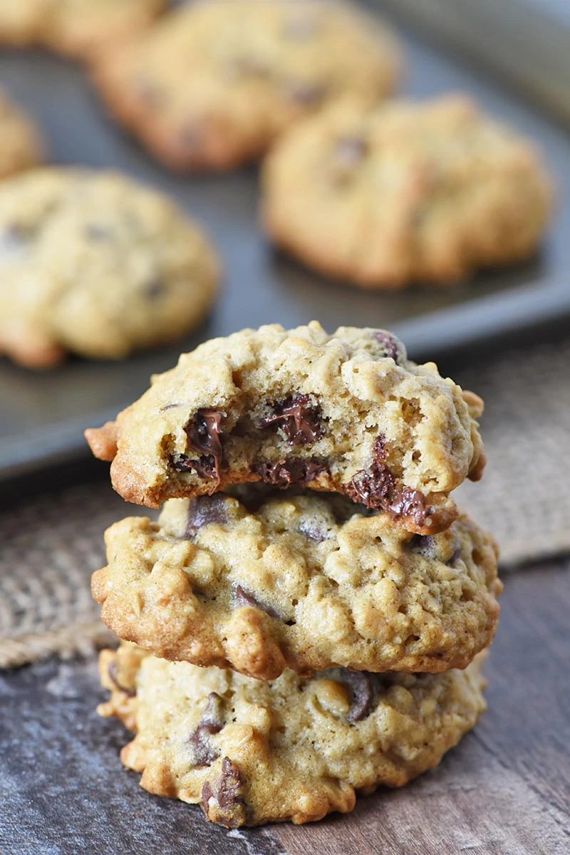 soft oatmeal chocolate chip cookies stacked on wooden countertop