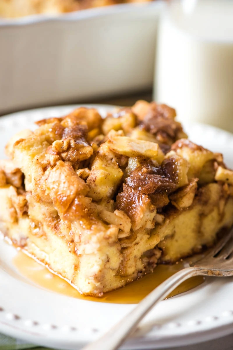 apple cinnamon breakfast casserole served with maple syrup on white plate with fork