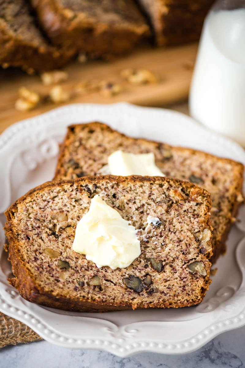 sliced dairy free banana bread lathered in butter on small white saucer
