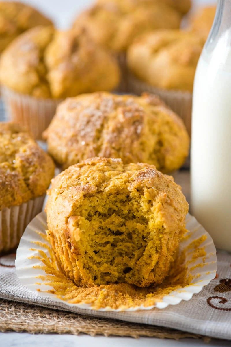 moist and fluffy inside of gluten-free pumpkin muffins on white cupcake liner with glass of milk