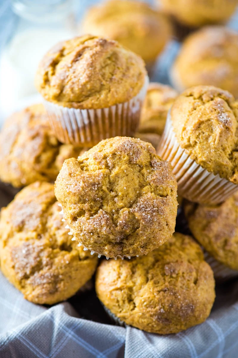 pile of pumpkin spice cake muffins in basket with fall kitchen towel