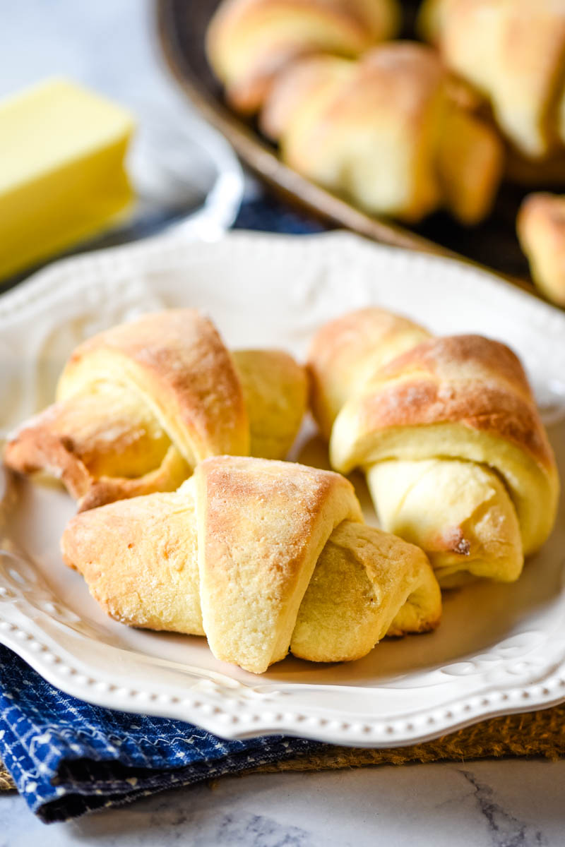 homemade crescent rolls on white plate served with butter