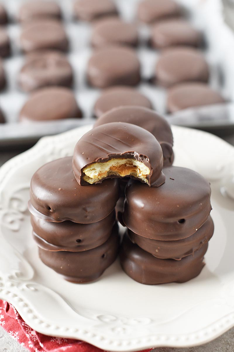 bite out of chocolate covered Ritz crackers with peanut butter, stacked on white plate