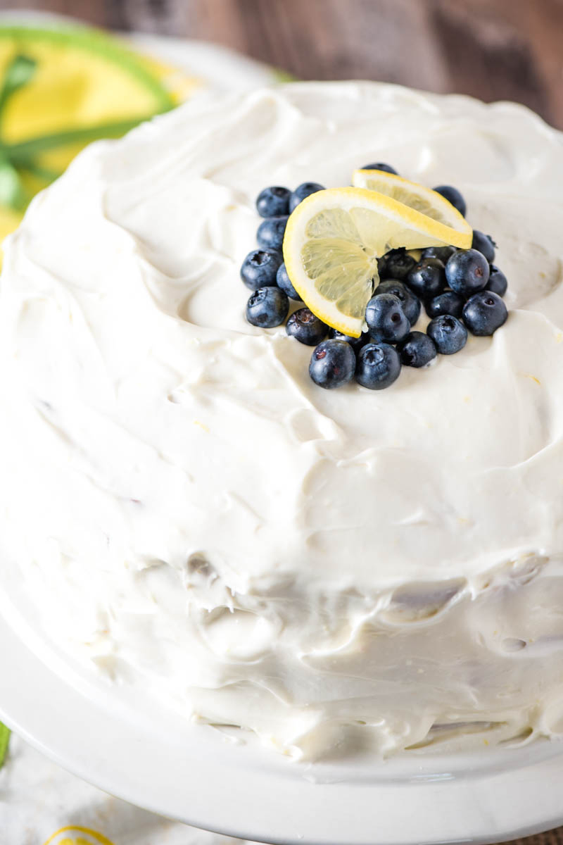 lemon blueberry cake with cream cheese frosting, topped with fresh blueberries and lemon slice