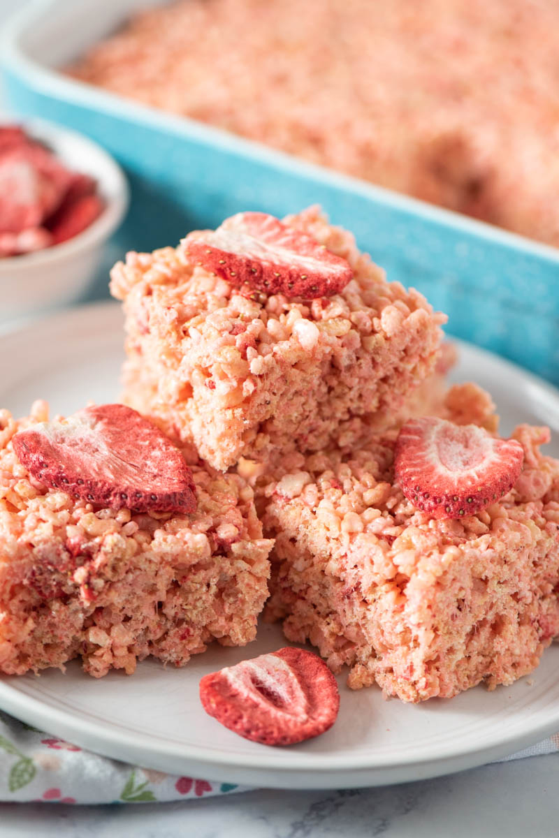 stack of Rice Krispie treats with freeze dried strawberries on top, on white plate