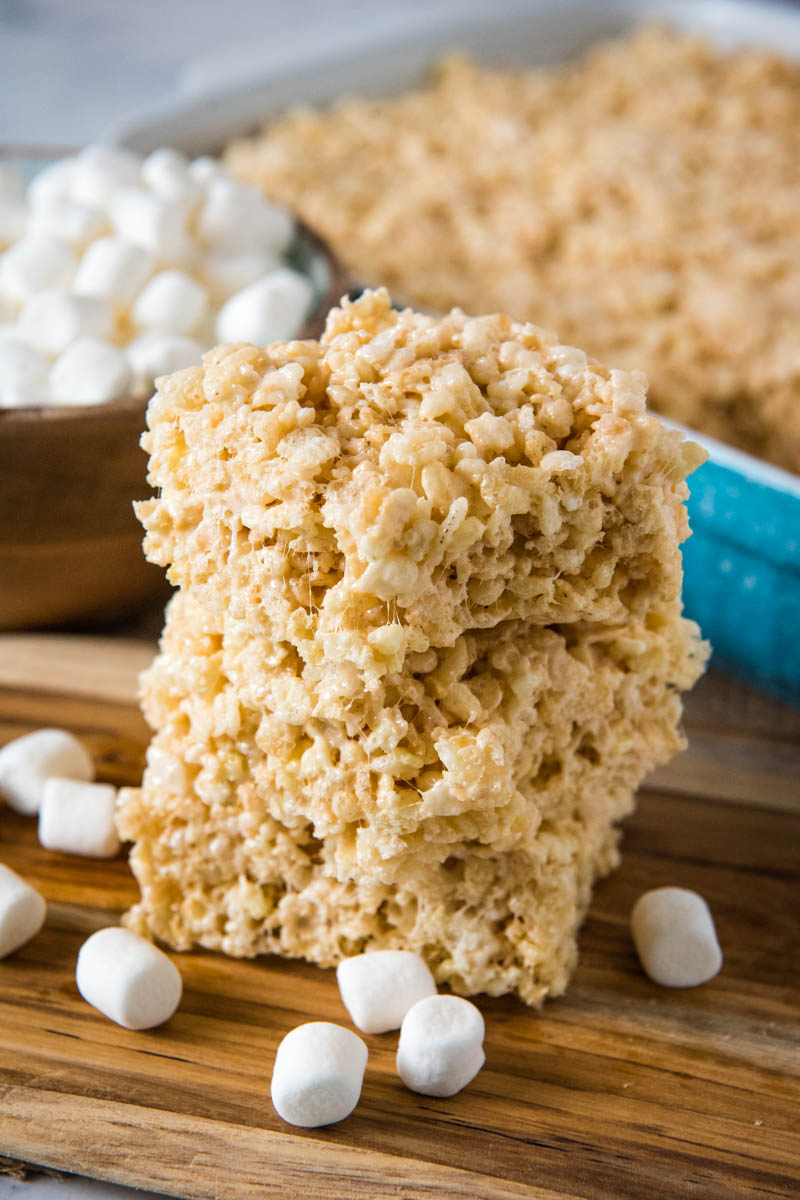 stack of microwave Rice Krispie squares on wooden cutting board with mini marshmallows