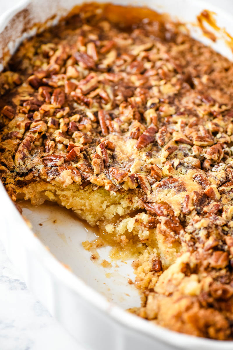 baked and scooped caramel apple dump cake with pecans in oval white baking dish