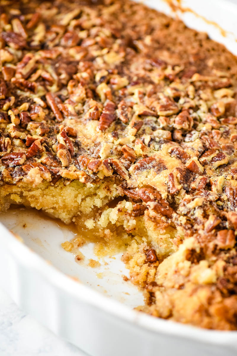 caramel apple pecan dump cake baked and scooped out of oval white baking dish