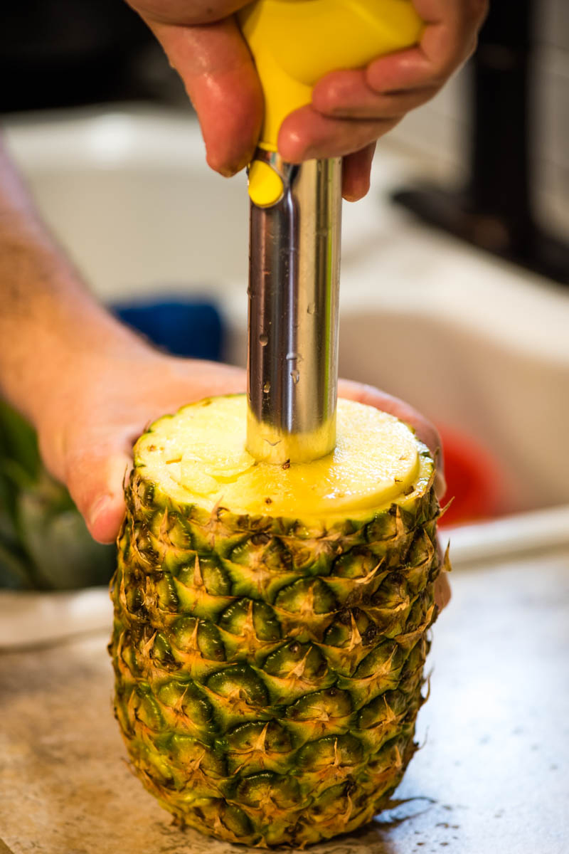 closeup photo of coring a pineapple with a pineapple corer
