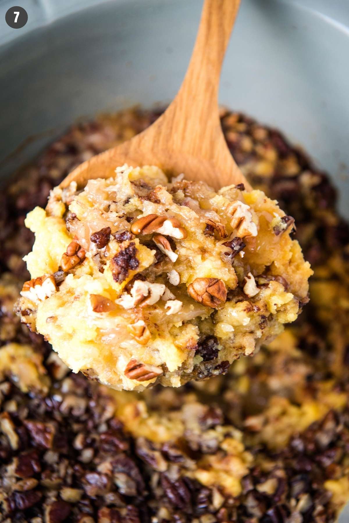 scooping Crock Pot apple dump cake out of gray slow cooker with wooden spoon