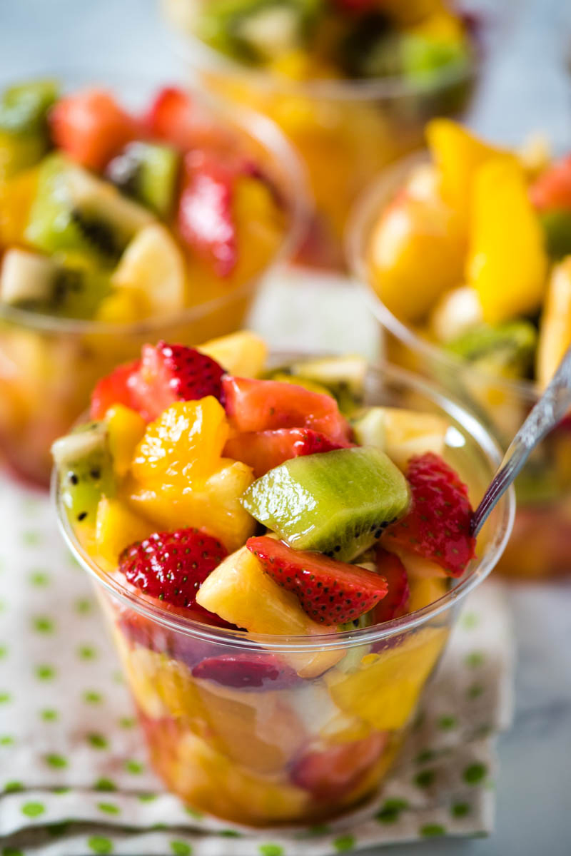 homemade fruit cups with tropical fruit in small plastic disposable cups on a white towel