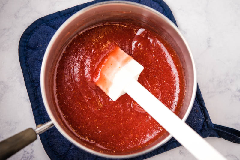homemade strawberry sauce in medium saucepan with white spatula