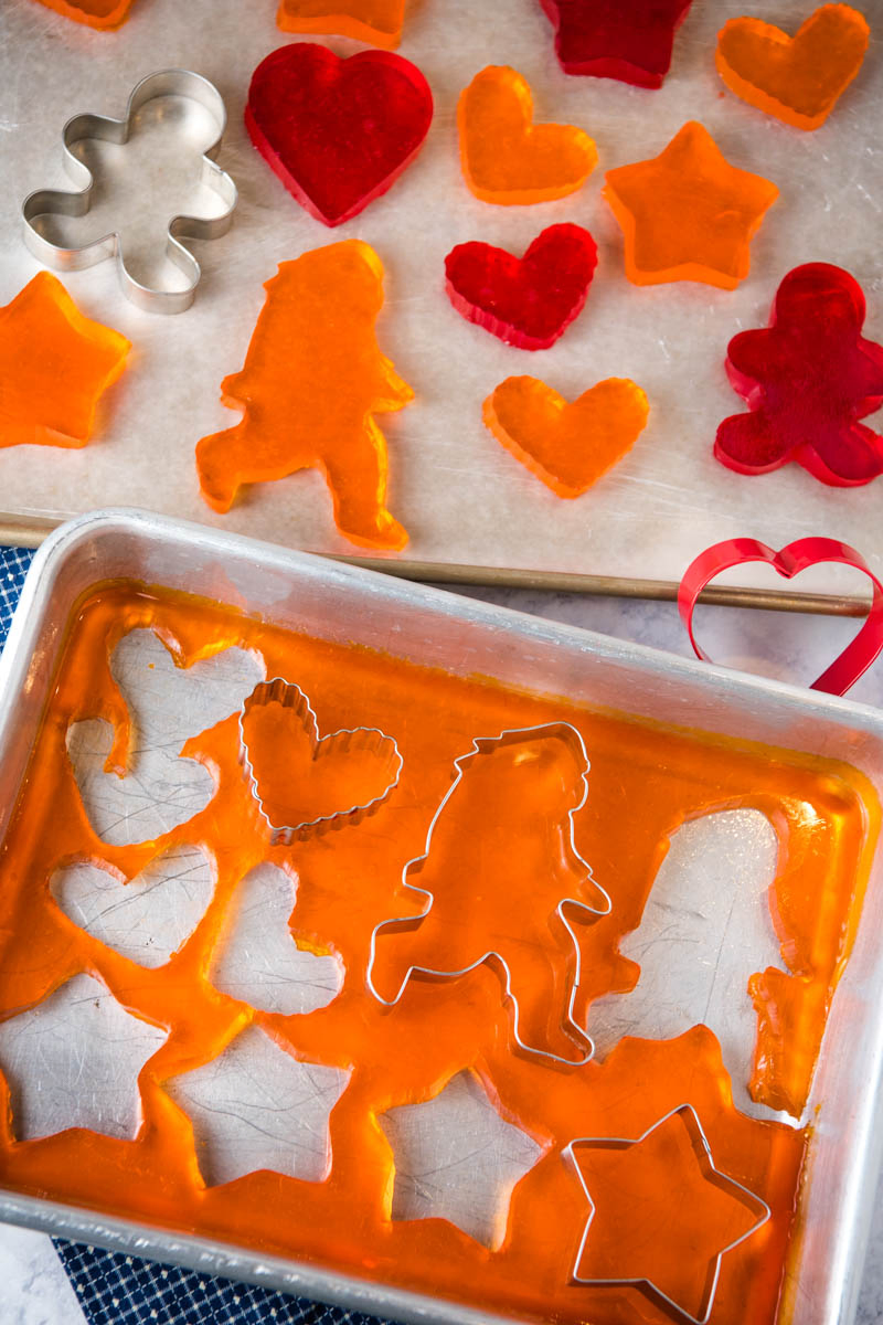 orange and cherry Jello Jigglers on baking sheet, heart and Bigfoot cookie cutters cutting out Jello Jigglers in baking pan