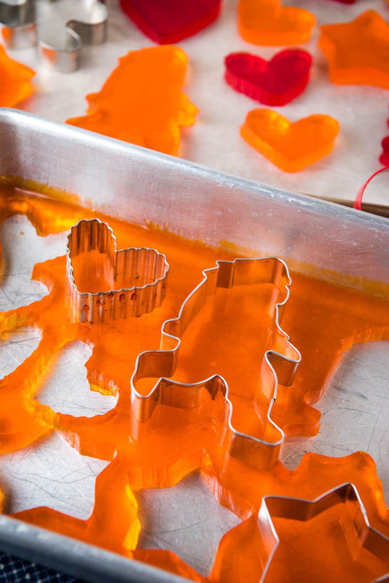 cutting out orange Jello Jigglers with Bigfoot and heart cookie cutters in metal cake pan