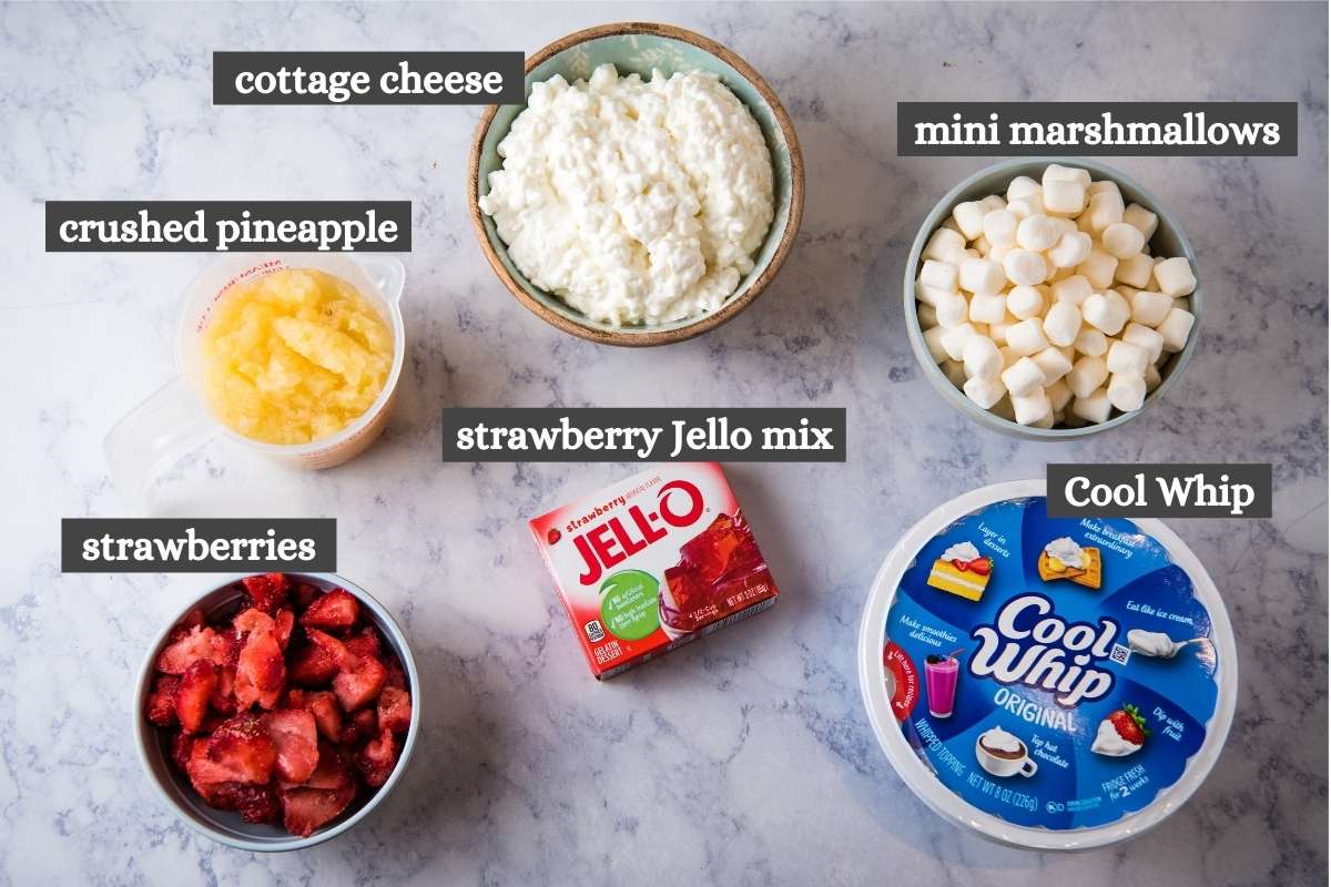 ingredients for strawberry cottage cheese salad on white marble countertop