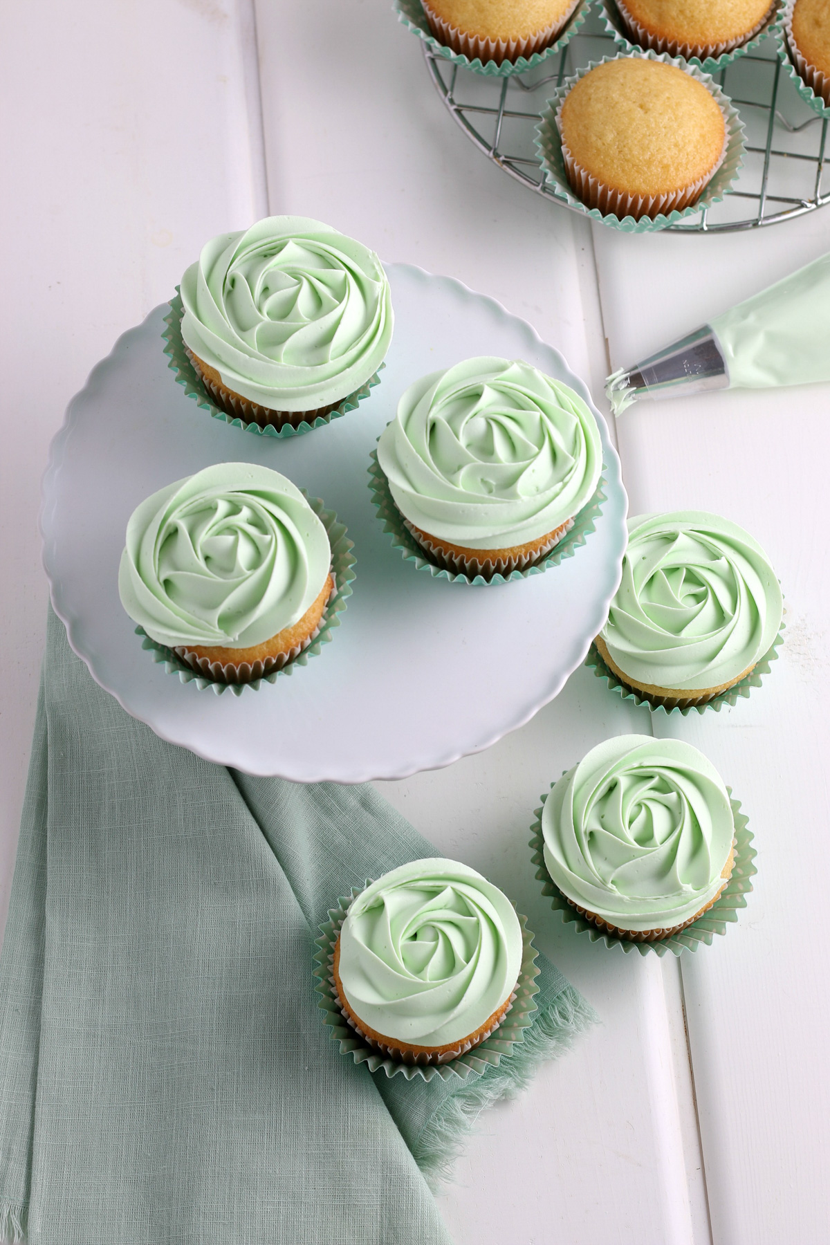 frosting vanilla cupcakes with green buttercream rosettes with pastry bag and 1M cake tip