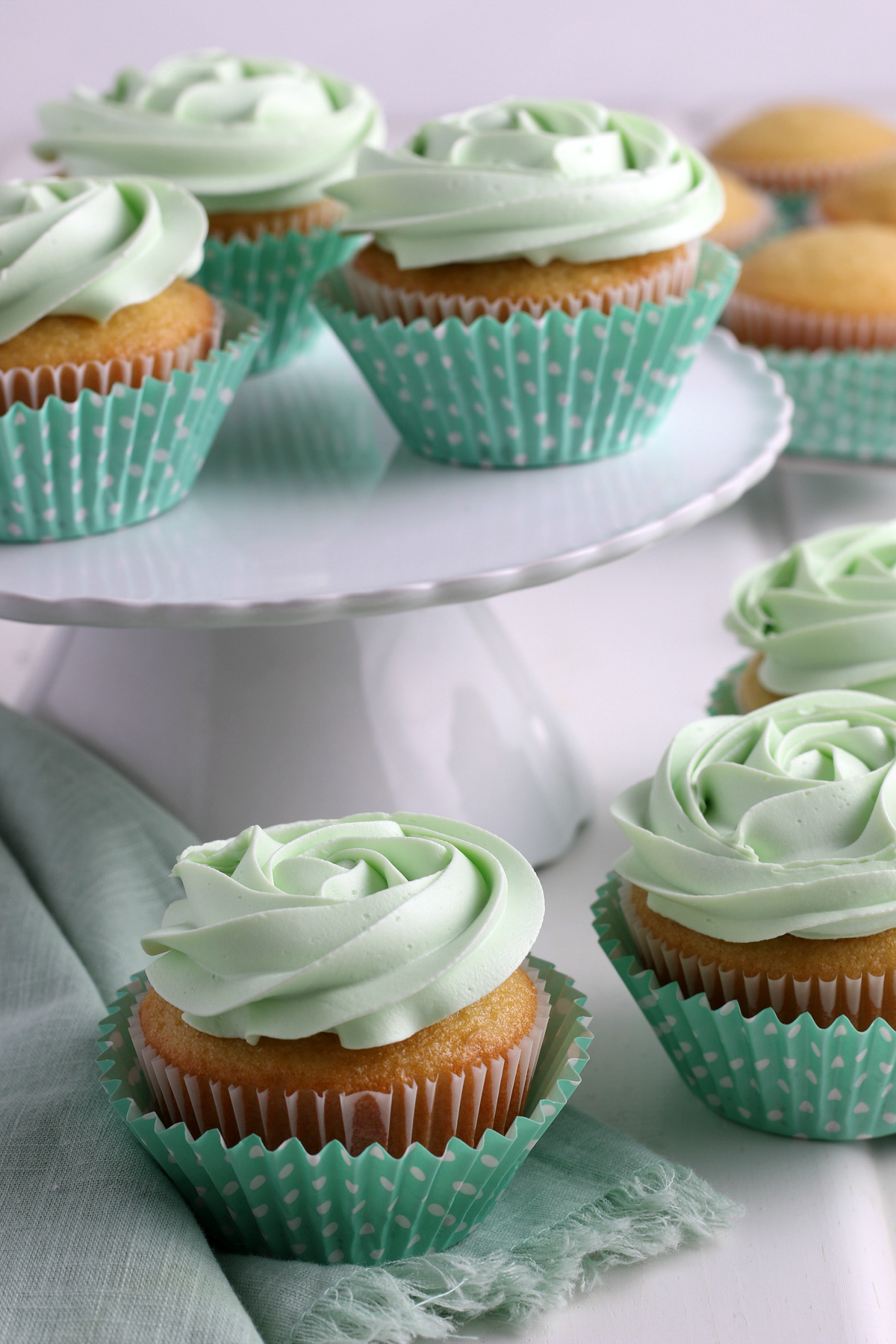gluten-free vanilla cupcakes topped with green buttercream rosettes, in sea green cupcake liners