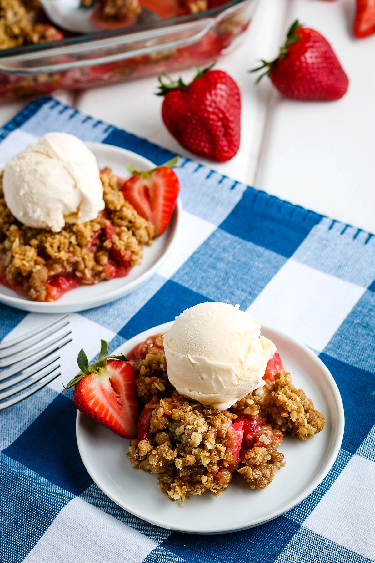 gluten-free rhubarb strawberry crisp topped with vanilla ice cream on gray plates