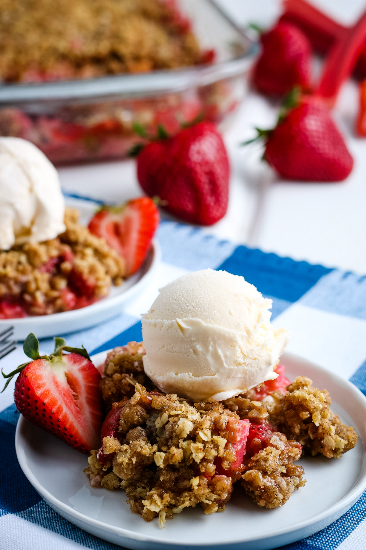 serving of gluten-free strawberry rhubarb crisp with scoop of vanilla ice cream on top, on gray plate