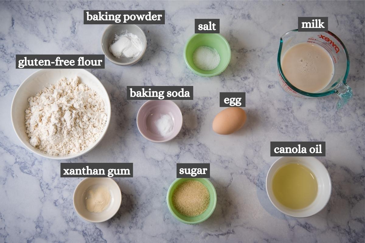 gluten-free American pancake recipe ingredients in small bowls on white marble countertop