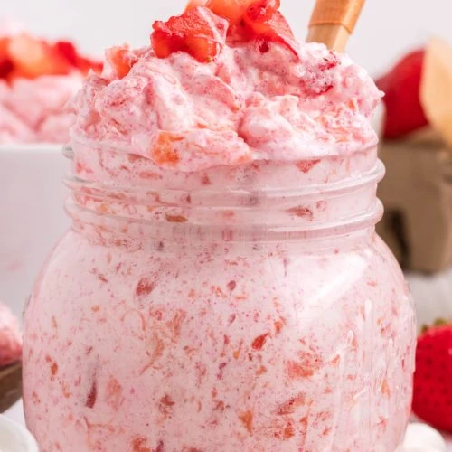 strawberry fluff in a small glass serving jar with fresh strawberry garnish on top