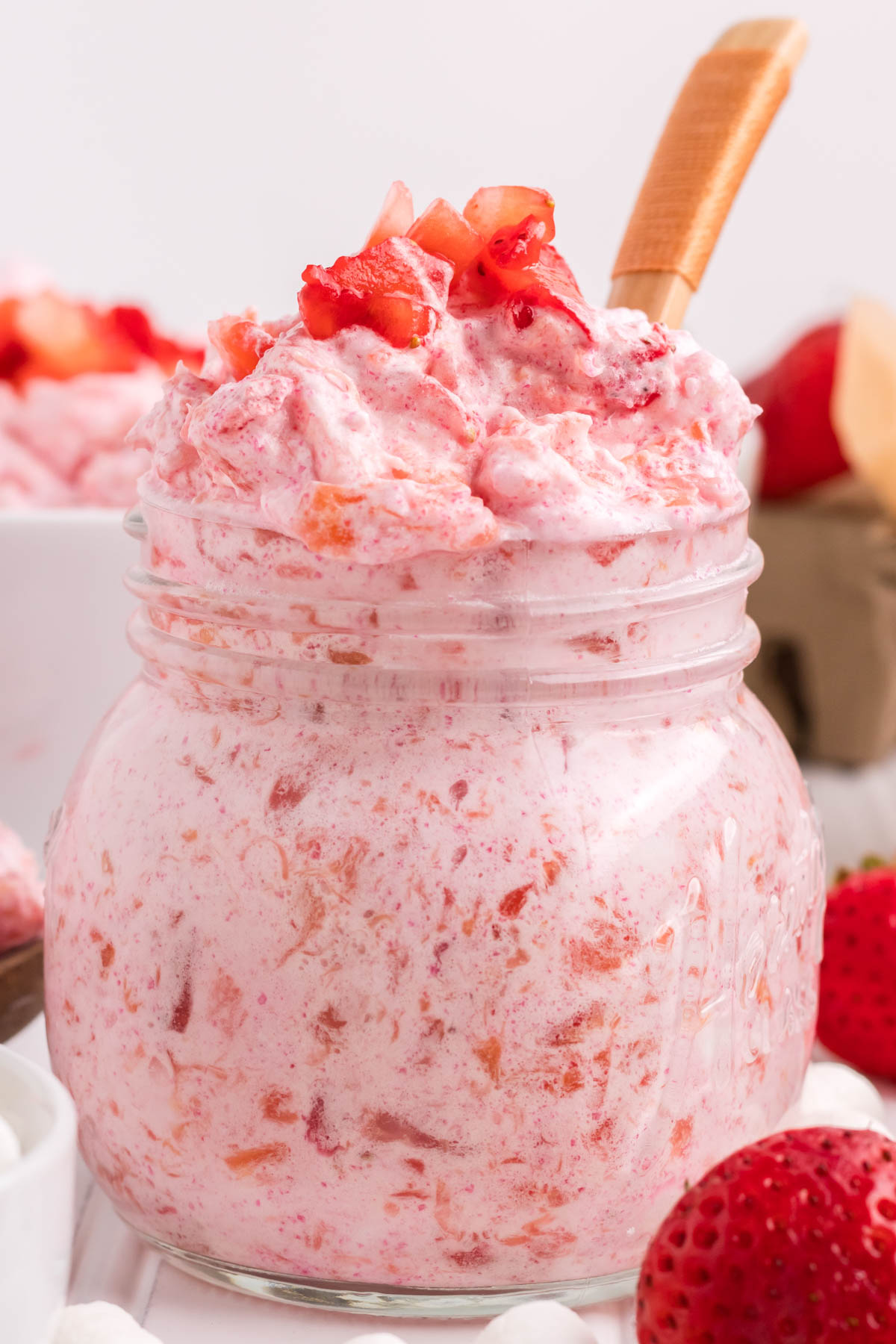 strawberry fluff in a small glass serving jar with fresh strawberry garnish on top