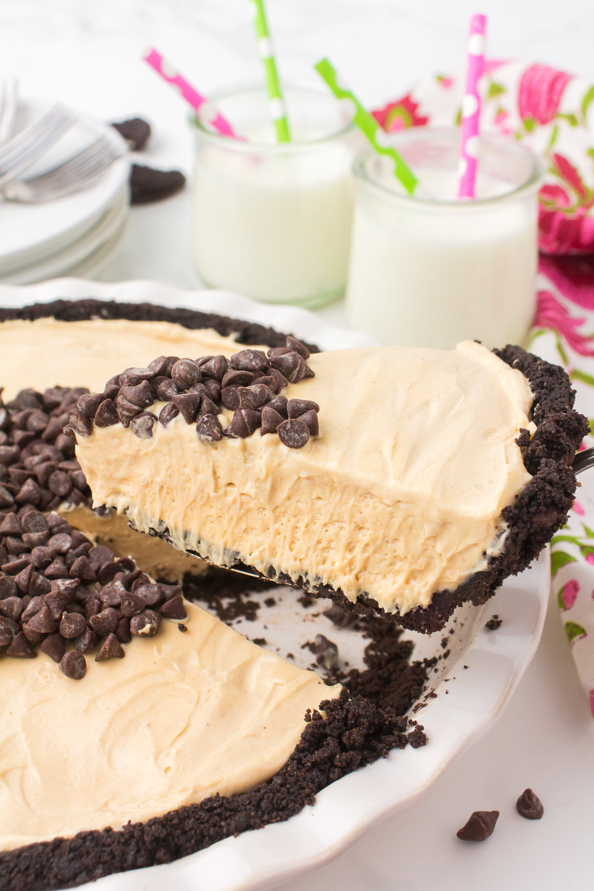 closeup photo showing holding a sliced wedge of no bake peanut butter pie over top of a white pie plate full of pie