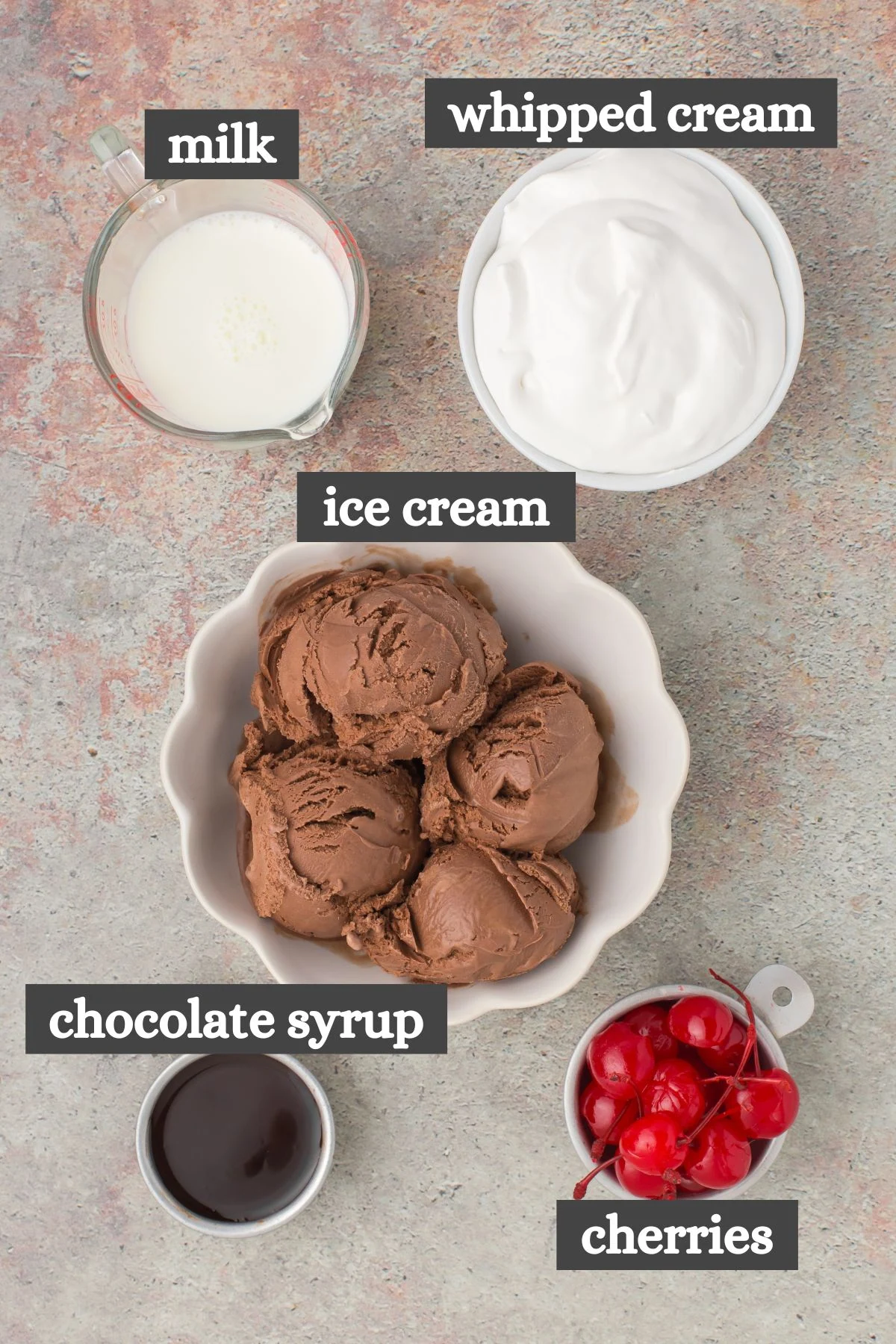 homemade chocolate milkshake ingredients lined out on a gray stone countertop