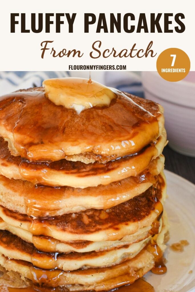 towering stack of fluffy pancakes lathered in butter and drizzled with maple syrup on a gray plate